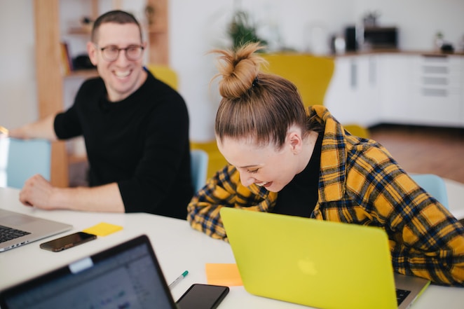 Dos personas ríen mientras trabajan